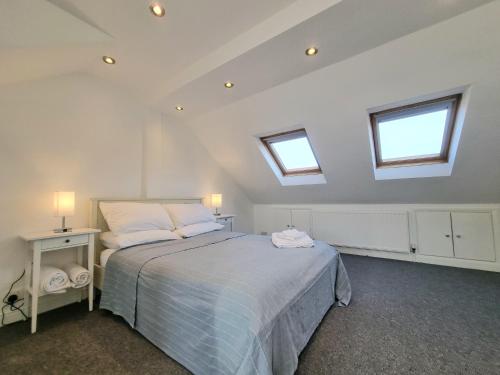 a bedroom with a bed with two pillows and two windows at The Loft in London