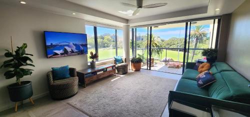 a living room with a green couch and a flat screen tv at Contemporary Harbourside Apartment in Sydney