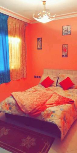 a bedroom with orange walls and a bed with red pillows at اقامة سوسن in Agadir