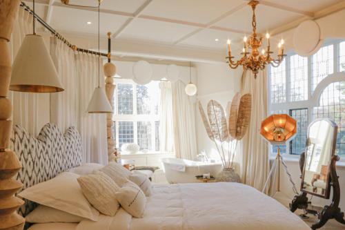 a bedroom with a large white bed with a chandelier at HIGHFIELD in Great Driffield