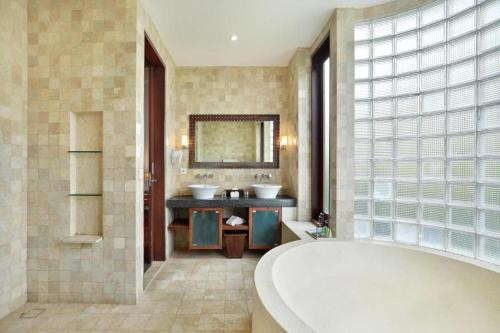 a bathroom with two sinks and a large tub at Sujiwana 2BR Luxury Jungle Pool View Villa CYN in Jimbaran