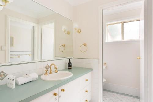 カトゥーンバにあるStunning Katoomba Home with Lush Garden&Playgroundの洗面台と鏡のある白いバスルーム