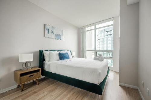 a white bedroom with a bed and a window at RivetStays - The Neptune in Toronto