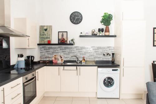 a white kitchen with a sink and a dishwasher at Lovely 2 bedroom apartment in Manchester