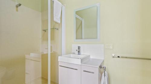 W białej łazience znajduje się umywalka i lustro. w obiekcie The Hide Away w mieście Kalimna
