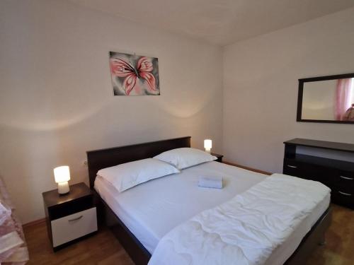 een slaapkamer met een wit bed met 2 lampen en een piano bij Apartments with a parking space Podstrana, Split - 22374 in Podstrana