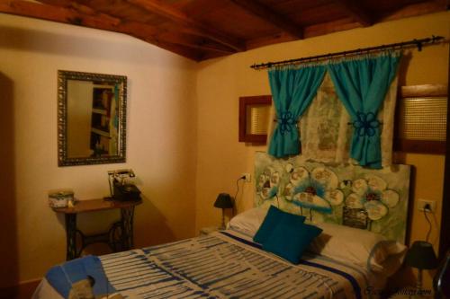 1 dormitorio con 1 cama con cortina azul en One bedroom chalet with terrace and wifi at Hermigua 3 km away from the beach, en Hermigua
