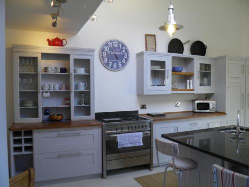 a kitchen with white cabinets and a stove at Holiday House Pembroke Dock in Pembroke Dock