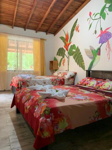 2 Betten in einem Zimmer mit Blumen an der Wand in der Unterkunft Hotel La Sultana in Jardin