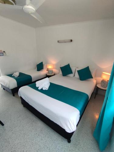 two beds in a room with two tables and two lamps at Nationwide Motel in Gympie