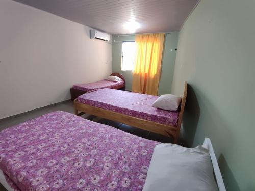 duas camas num pequeno quarto com lençóis roxos em Casa Cactáceas em Encarnación