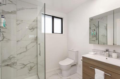 a bathroom with a toilet and a glass shower at Light & Spacious 2Bdrm Townhouse Off Street Park in Christchurch