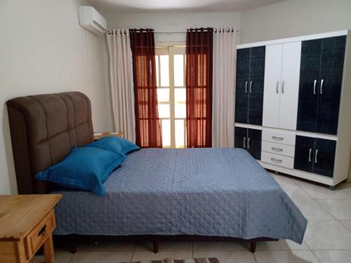 ein Schlafzimmer mit einem Bett mit blauen Kissen in der Unterkunft Férias!! Inspire-se e Renove! 7km centroMar Torres RS in Torres