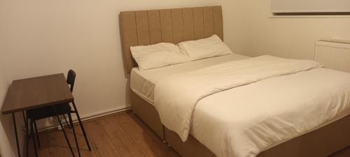 Bett in einem kleinen Zimmer mit einem Schreibtisch und einem Bett sidx sidx sidx in der Unterkunft Croydon Homestay-Shared Apartment with Shared Bathroom in South Norwood