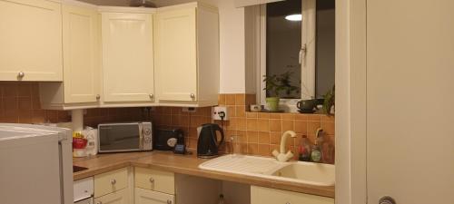 a kitchen with white cabinets and a sink at Croydon Homestay-Shared Apartment with Shared Bathroom in South Norwood