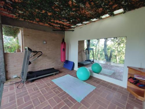 a room with a gym with a television and a brick wall at Champagny Pousada in Santo Antônio do Pinhal
