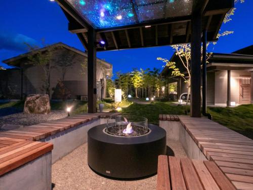 eine Terrasse mit einer Feuerstelle in der Mitte eines Gartens in der Unterkunft Yumotoan Kiyohime in Kirishima