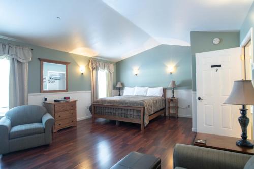 a bedroom with a bed and a couch and a chair at Swift River Suites in Rumford