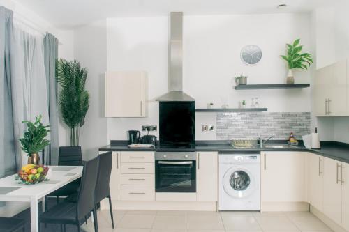 een keuken met witte kasten en een tafel met een wasmachine bij Modern and Spacious 2 bedroom Apartment, Close to Stadiums, Transport links, Free Parking in Manchester