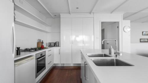 a white kitchen with a sink and a stove at Mollymook Breeze in Narrawallee