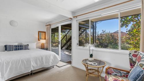a bedroom with a bed and a large window at Mollymook Breeze in Narrawallee