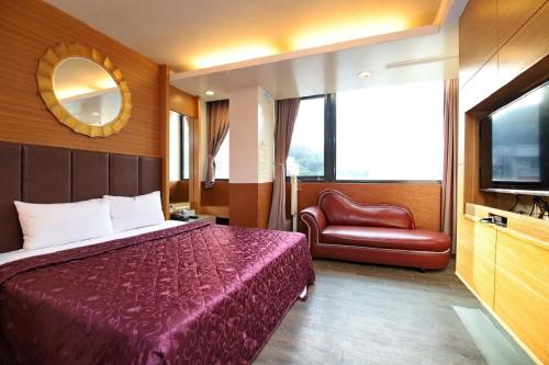 a bedroom with a bed and a chair and a television at Yosemite Hot Spring Resort in Baihe