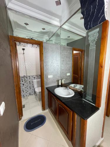 een badkamer met een wastafel, een toilet en een spiegel bij Coastal Comfort Rentals! in Tanger