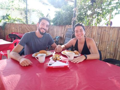 un hombre y una mujer sentados en una mesa roja con comida en HOSTAL SARITA, en Villavieja