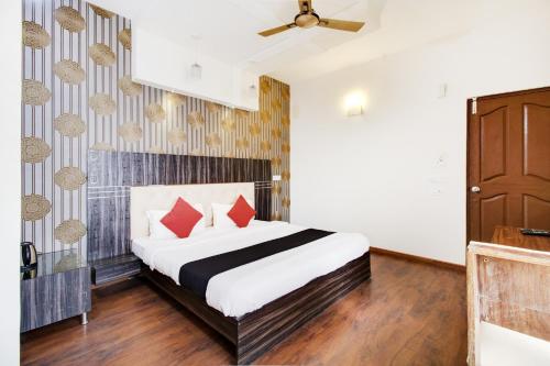 - une chambre avec un lit et des oreillers rouges dans l'établissement Capital O Hotel Shanti Nivas Near Hare Krishna Hill, à Bangalore