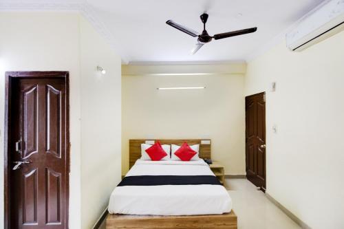 - une chambre avec un lit doté d'oreillers rouges et d'un ventilateur de plafond dans l'établissement Capital O Hotel Shanti Nivas Near Hare Krishna Hill, à Bangalore