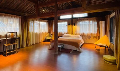 - une chambre avec un lit dans une pièce dotée de fenêtres dans l'établissement Qushe Snowy Mountain View Art B&B, à Lijiang