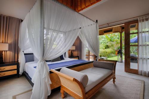 - une chambre avec un lit à baldaquin, un canapé et une fenêtre dans l'établissement Villa Maya Scenic in Canggu, à Dalung