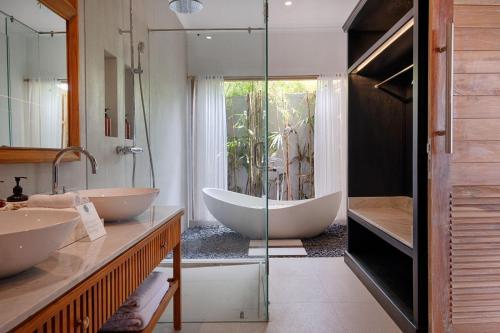 une salle de bain avec deux lavabos et une baignoire dans l'établissement Villa Maya Scenic in Canggu, à Dalung