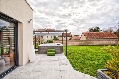 une cour avec un bain à remous et une pelouse dans l'établissement Villa Howard — Jacuzzi, Tranquility & Parking, à Ranville