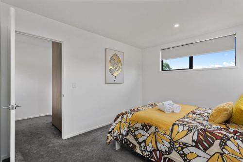 a bedroom with a bed with a yellow blanket and a window at Luxury Style Free Street Parking CBD Location in Christchurch