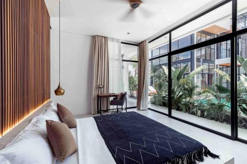 a bedroom with a bed and a large window at Baliwood Villas - OCEAN VIEW 3BR in Canggu