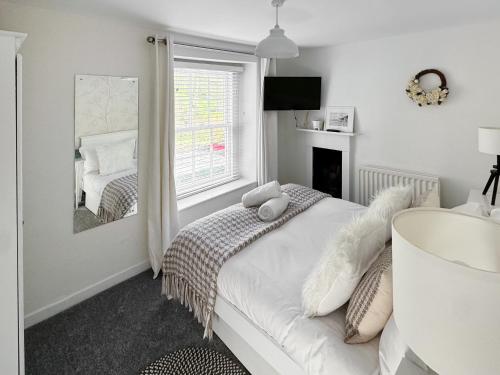 a white bedroom with a bed and a mirror at Driftwood in Aberdyfi