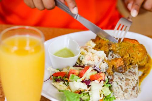 a plate of food with rice and a salad and a drink at La Flamboyant Hotel in Roseau