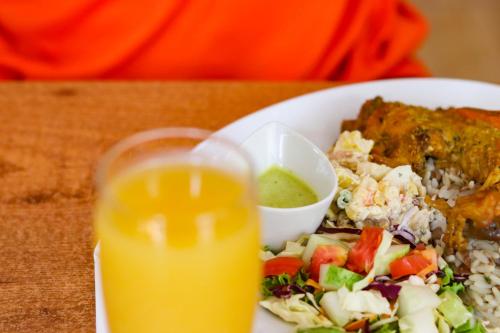 a plate of food and a glass of orange juice at La Flamboyant Hotel in Roseau