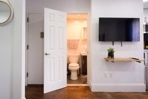 a bathroom with a toilet and a tv on a wall at 69-3B Prime Lower East Side BRAND NEW 1br Apt in New York