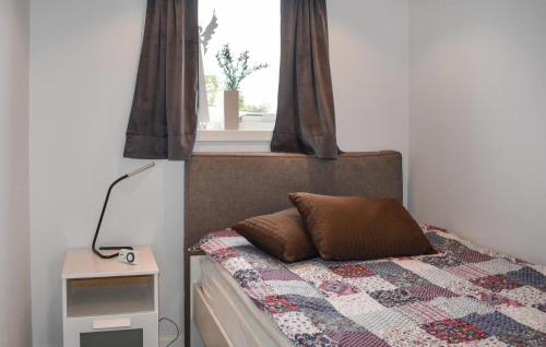 een slaapkamer met een bed met een quilt en een raam bij Nice Home In Slvesborg With Kitchen in Sölvesborg