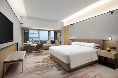 a bedroom with a large white bed and a living room at voco Changsha Airport, an IHG Hotel in Changsha