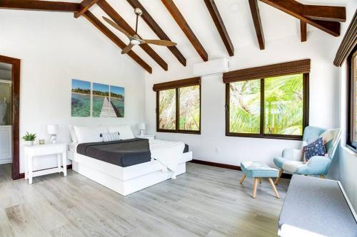 a white bedroom with a bed and a chair at Photo Perfect-Beachfront 2 Bedroom-Infinity Pool in Placencia Village