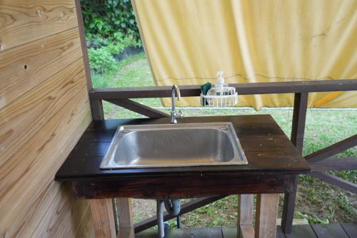 eine Küchenspüle auf einem Holztisch mit einem Fenster in der Unterkunft ASOBI HACK 