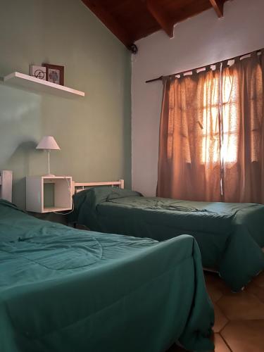 dwa zielone łóżka w pokoju z oknem w obiekcie ALQUILER LAS FLORES w mieście Las Flores