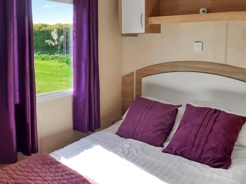 a bedroom with a bed with purple curtains and a window at Wren - Uk41949 in Louth