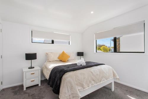 a white bedroom with a bed and a window at Charming Sunny Warm 10 Mins CBD Book Now in Christchurch