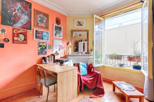 Habitación con paredes de color naranja, escritorio y ventana. en Résidor - Apartment in the heart of Montmartre, en París