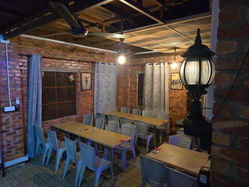 una sala in mattoni con tavoli, sedie e lampada di Heritage House Windcave Bar & Stay a Bau