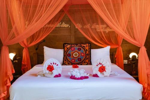 a bed with orange curtains and white pillows on it at Bali Bohemia Huts in Ubud